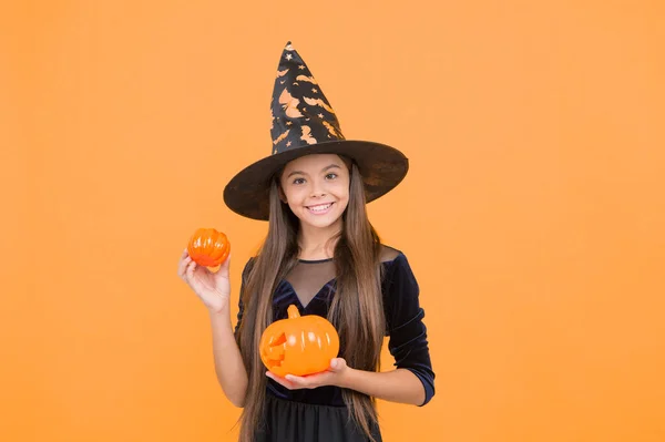halloween witch girl. happy childhood. teenage child in witch hat. cheerful kid holding pumpkin. carnival costume party. trick or treat. celebrate the holidays. jack o lantern. Please Come For A Bite.
