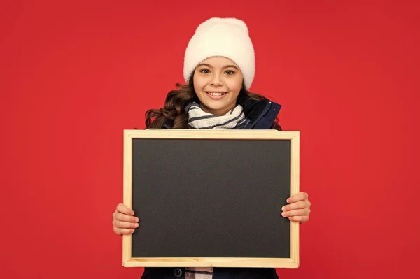 陽気な子供を学校に 発表と広告です 冬の売り上げ 帽子を被った黒板の子供 十代の女の子持株黒板とともにコピースペース — ストック写真