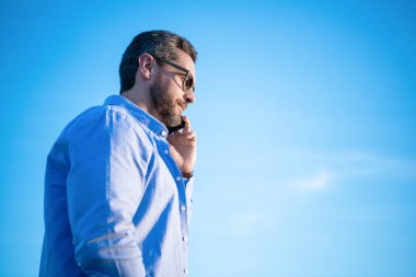 Telefonda boz adam sohbeti. Adam akıllı telefondan konuşuyor. Gökyüzü arka planında insan iletişimi. Boşluğu kopyala.