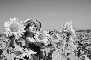 Doğanın bir parçası. Sarı çiçeklerin arasında saman şapkalı neşeli çocuk. Yaz ayçiçeği tarlasında küçük bir kız. Mutlu çocuklar günü. çocukluk mutluluğu. Güzel ayçiçekli mutlu çocuk portresi.