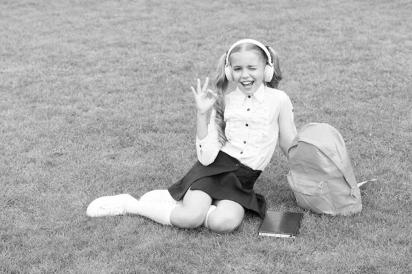 穿着校服的快乐女孩端坐在绿草上 心满意足 — 图库照片