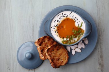 Kremalı balkabağı kremalı çorba, siyah kimyon tohumları, otlar ve kızarmış ekmek.