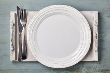 Beyaz ahşap tepside çatal bıçaklı el yapımı beyaz seramik tabak. Menü. Üst görünüm