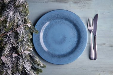 Mavi tabak, çatal bıçak takımı ve açık mavi ahşap masada noel ağacı. Noel yemeği. Düz yatıyordu