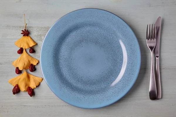 Boş mavi tabak, çatal bıçak takımı ve Noel ağacı.