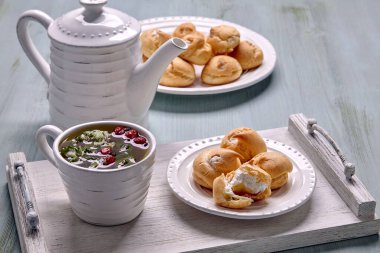 Kremalı profiterol ve bir fincan bitkisel çay.
