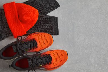 Turuncu örülmüş sıcak şapka, sıcak spor taytları ve turuncu koşu ayakkabıları.