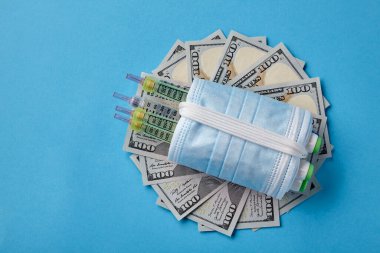 İnsülin şırıngaları dolar banknotlarına sarılı tıbbi maskeler.