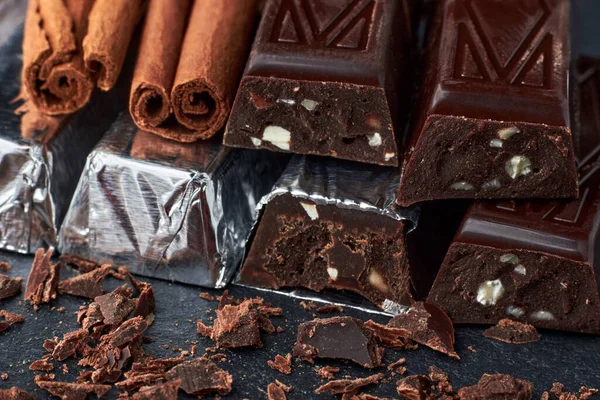 Barras de chocolate escuro com amêndoas picadas e paus de canela — Fotografia de Stock