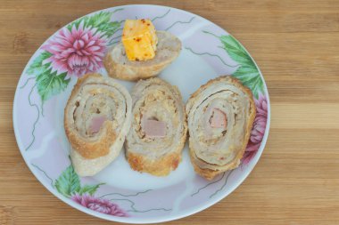 Üç dilim dilimlenmiş köfte ve tabakta bir parça peynir.