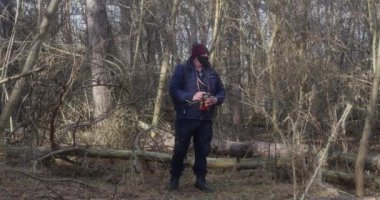  Koruyucu maskeli bir gezgin çam ormanında geçmişe dönük bir kamerayla yürüyor..