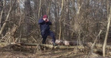 Güzel bir çam ormanında bir adam film kamerasıyla fotoğraf çeker..