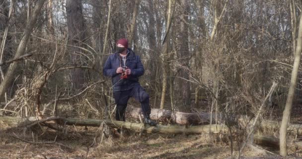 美しい松林の中の保護マスクの男がレトロなフィルムカメラで写真を撮る — ストック動画