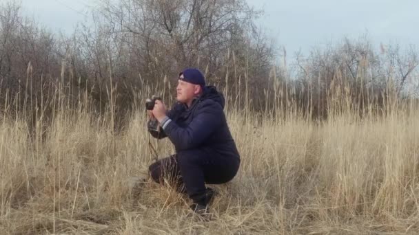 男はレトロなカメラ側の眺めで葦の近くで写真を撮る — ストック動画