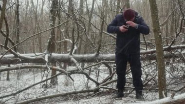  Bir turist, güzel bir kar yağışı sırasında ormandaki retro iki lensli kamerayla fotoğraf çeker.