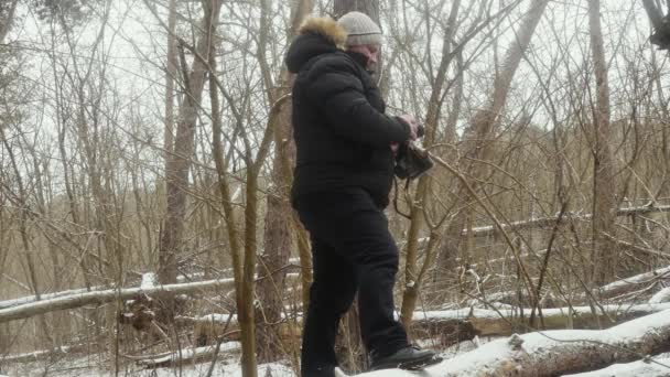 Turysta Leżącym Zaśnieżonym Drzewie Robi Zdjęcia Starej Kamerze Filmowej — Wideo stockowe