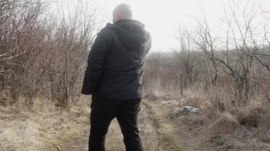 Neşeli bir adam yolda yürür ve cep telefonuyla konuşur..