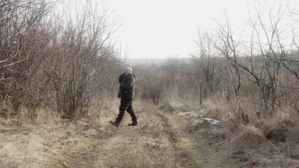 陽気な男が携帯電話で話をし木に触れる道を歩き — ストック動画
