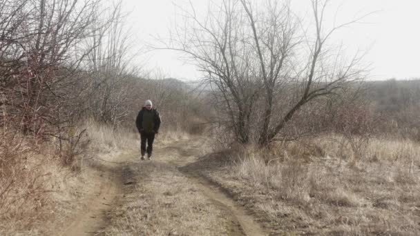 ポケットに手を入れた男が森の道を自然に歩き — ストック動画