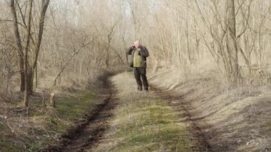 Ormanda cep telefonuyla biriyle tartışan bir adam..