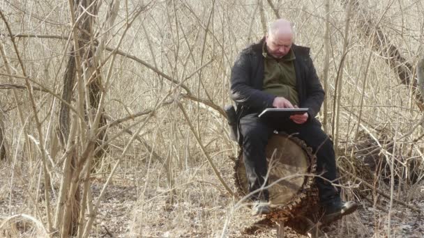 Hombre Bosque Sin Hojas Sentado Tocón Grande Mira Sus Fotos — Vídeos de Stock