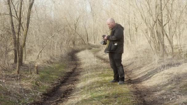 森の中の男がレトロなフィルムカメラで写真を撮り — ストック動画