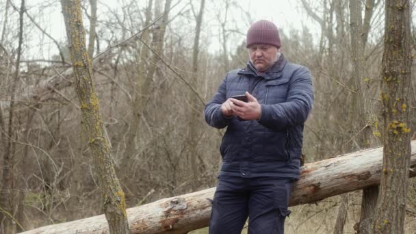 Hombre Bosque Mirando Través Fotos Teléfono Mientras Está Sentado Pino — Vídeos de Stock