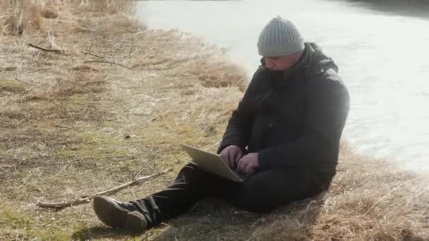 Ein Mann Sitzt Auf Gelbem Gras Und Arbeitet Einem Laptop — Stockvideo