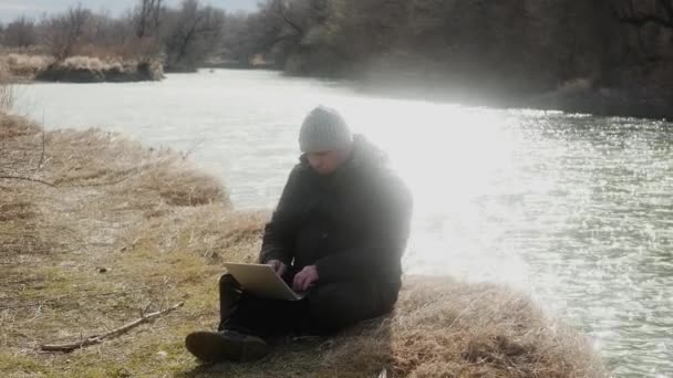 Man Sits Grass Lit Sun Works Laptop River Bank Concept — Stock Video