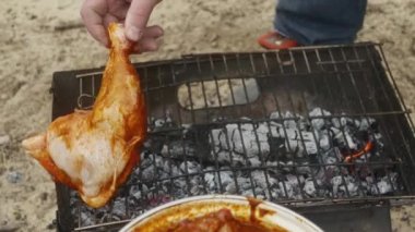 Bir el tavuk bacağını ızgaraya ketçapla marine eder.