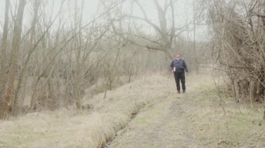 Elinde kitap olan bir gezgin orman yolunda ilerler..