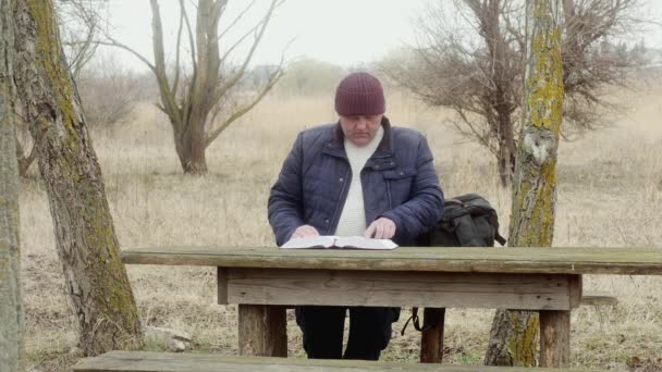 Muž Venku Čte Knihu Zájmem Sedící Dřevěného Stolu Mezi Stromy — Stock video