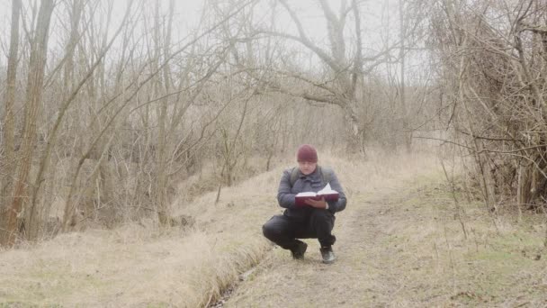 Een Reiziger Leest Een Dik Boek Terwijl Hij Hurkt Een — Stockvideo