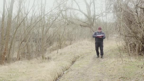 本を読む旅人は森の道を下り — ストック動画