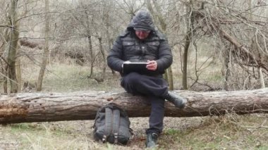 Bir gezgin, hafif bir kar yağışı sırasında çam ağacında oturan trafo bilgisayarında bir şeye bakar.