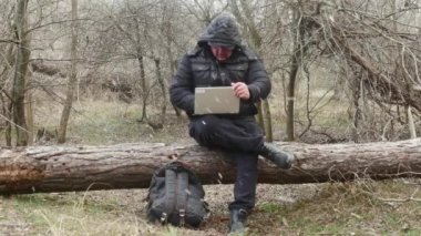  Bir gezgin kar yağışı sırasında yalan söyleyen bir çam ağacında otururken dizüstü bilgisayarında bir şey yazıyor..