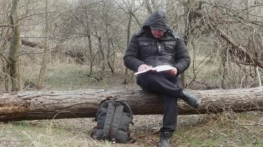  Gezgin, kitaptaki sayfaları karıştırır. Bahar ormanı başlarında bir çam ağacında oturur.