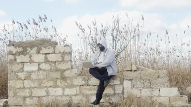 Ein Mann Mit Kapuze Und Maske Sitzt Draußen Auf Einer — Stockvideo