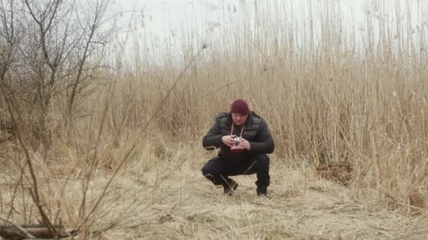 自然界の男が葦湖を背景にヴィンテージフィルムカメラで写真を撮る — ストック動画
