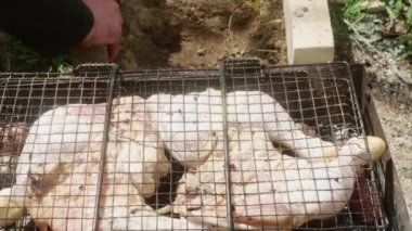 Izgaranın yanındaki ateş çukurunda çiğ tavuk bacağı var.