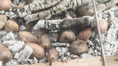 potatoes in hot ashes in a pit under the grate with chicken legs