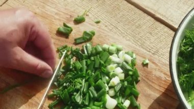 Bıçaklı bir el salata için tahta bir tahtada bahar pırasası keser..