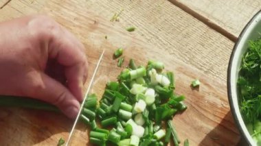 Bıçaklı bir el bahar salatası için tahta bir tahtada bahar pırasası keser.