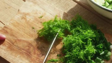 Elinde bıçak olan bir el salatalık kesmek için tahta bir masaya salatalık koyar..