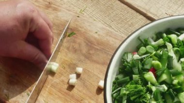 Şef salata için tahta üzerinde pırasa kesiyor..