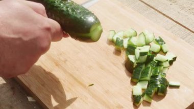  Bir adamın eli bir salatalığı bıçakla keser.