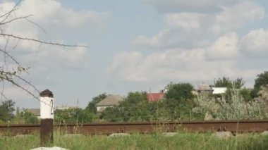 time lapse of the movement of white clouds over the old railway rails against the backdrop of the village.