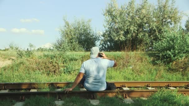 Tourist Talking Mobile Phone While Sitting Soviet Old Railway Rails — Videoclip de stoc