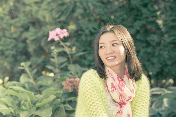 Woman sitting next to a garden — Stock Photo, Image