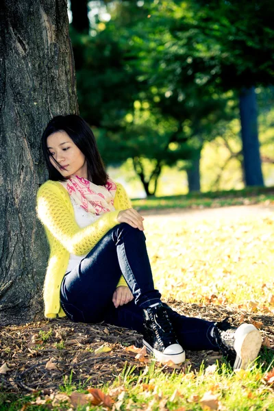 Mujer sentada contra un árbol — Foto de Stock